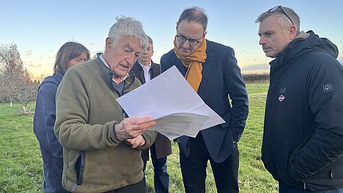 Ian and others in a field looking at some documents