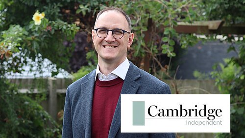Ian Sollom MP in front of bushes and trees, with the Cambridge Independent logo emblazoned on the bottom right