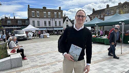 Ian in St Neots Market Square with the market going on behind him